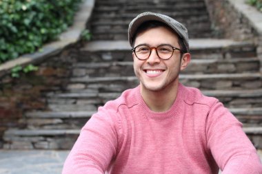 Şehir caddesinde sıradan kıyafetler giymiş yakışıklı bir gencin yakın plan portresi.