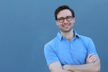 Mavi duvarın önünde sıradan giyinmiş yakışıklı bir gencin yakın plan portresi.