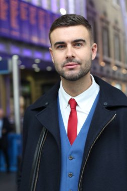 Takım elbiseli ve ceketli yakışıklı genç iş adamının yakın plan portresi.