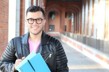 Şehir sokaklarında dosyasıyla günlük giysiler içinde yakışıklı bir gencin yakın plan portresi.