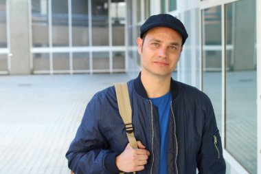 Yakından çekilmiş, sıradan kıyafetler giymiş ve şapkalı yakışıklı genç bir adam portresi.