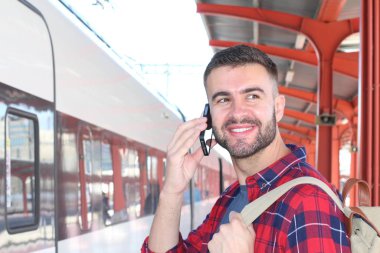 Tren istasyonunda sırt çantalı yakışıklı bir gencin yakın plan portresi.