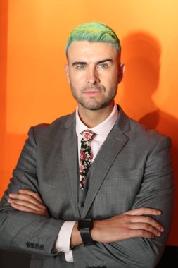 Turuncu arka planda duran yeşil saçlı zarif yakışıklı adam.