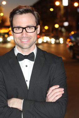 smokinli ve papyonlu yakışıklı bir delikanlının akşam vakti şehir caddesinde yakın plan fotoğrafı.