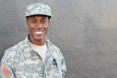 Gri duvarın önündeki yakışıklı Afro-Amerikan askerinin yakın plan portresi.