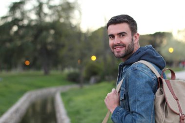 Akşam vakti sırt çantalı yakışıklı bir gencin yakın plan portresi.