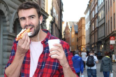 Etnik erkek dışarıda sosisli yiyor.