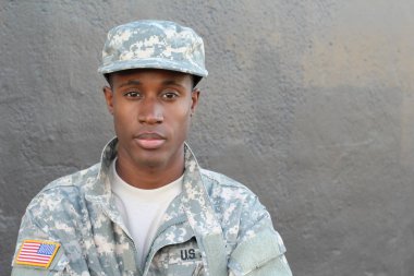 Gri duvarın önündeki yakışıklı Afro-Amerikan askerinin yakın plan portresi.