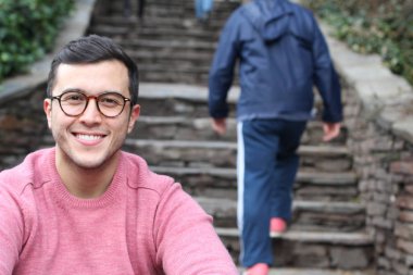 Şehir caddesinde sıradan kıyafetler giymiş yakışıklı bir gencin yakın plan portresi.