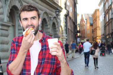 Etnik erkek dışarıda sosisli yiyor.