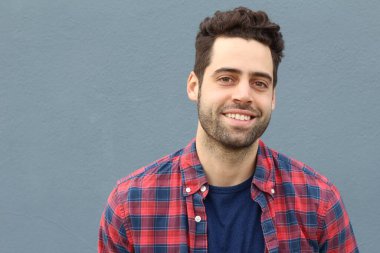 Gri duvarın önündeki yakışıklı genç adamın yakın plan portresi.