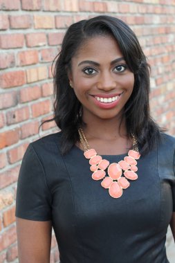 Tuğla duvar arkasında kendine güvenen zarif, genç, siyah bir kadın.