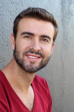 Gri duvarın önündeki yakışıklı genç adamın yakın plan portresi.