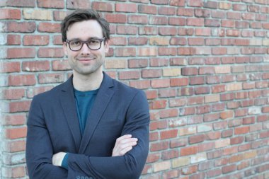 Tuğla duvarın önünde yakışıklı genç işadamının yakın plan çekimi.