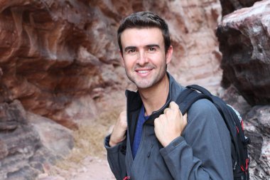 Grand Canyon travel. Happy man mountain hiker with backpack on rocky dry mountains