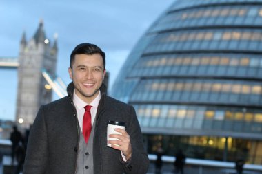 Londra 'daki Tower Bridge' in önünde elinde bir fincan kahveyle yakışıklı genç işadamının yakın plan portresi.
