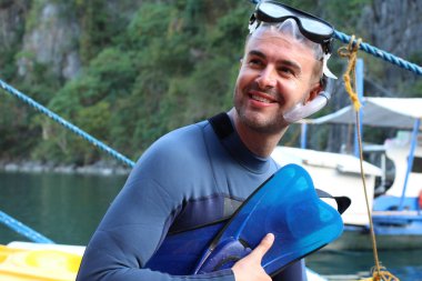 Teknede şnorkel ve maskeli yakışıklı genç adamın yakın plan portresi.