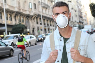 Sokakta tıbbi güvenlik maskesi takmış yakışıklı genç adamın yakın plan portresi.