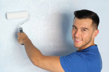 Neşeli etnik erkek evinde bir duvar boyamak üzere.