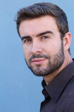 Duvarın önündeki yakışıklı sakallı adamın yakın plan portresi.