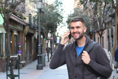 Avrupa 'nın caddesinde günlük kıyafetlerle konuşan yakışıklı genç adamın yakın plan portresi.