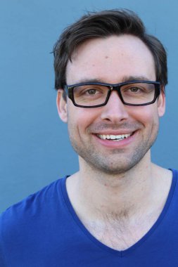 Mavi duvarın önünde sıradan giyinmiş yakışıklı bir gencin yakın plan portresi.