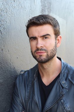 Duvarın önündeki yakışıklı sakallı adamın yakın plan portresi.