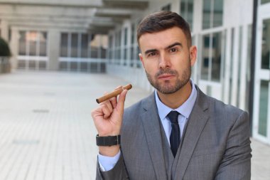 Yakışıklı genç işadamının sokakta puro içerken yakın plan portresi.