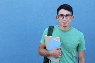 Mavi duvarın önünde sırt çantalı yakışıklı bir gencin yakın plan portresi.