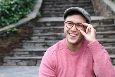 Şehir caddesinde sıradan kıyafetler giymiş yakışıklı bir gencin yakın plan portresi.