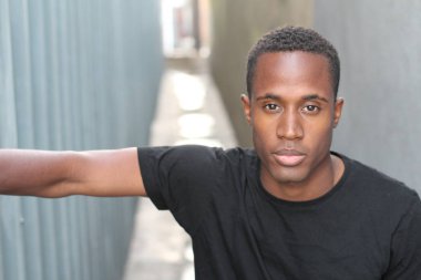 Sokakta siyah tişörtlü yakışıklı Afro-Amerikan adamın yakın plan portresi.