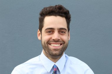 Gri duvarın önünde bej takım elbiseli yakışıklı genç işadamının yakın plan portresi.