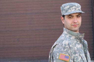 close-up portrait of handsome young soldier in front of brown wall