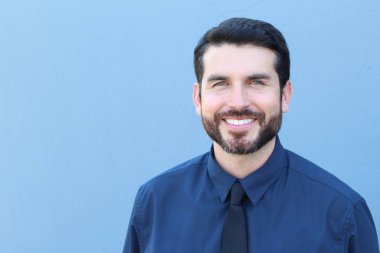 Kendine güvenen genç işadamı mavi arka planda gülümsüyor ve kopya için yer var.