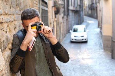 Eski şehir caddesinde kameralı yakışıklı bir gencin yakın plan portresi.