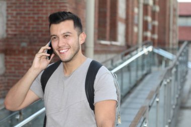 Sokakta telefonla konuşan, günlük kıyafetler içindeki yakışıklı genç adamın yakın plan portresi.