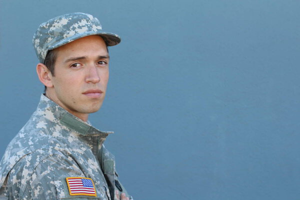 close-up portrait of handsome young soldier in uniform and cap in front of blue wall