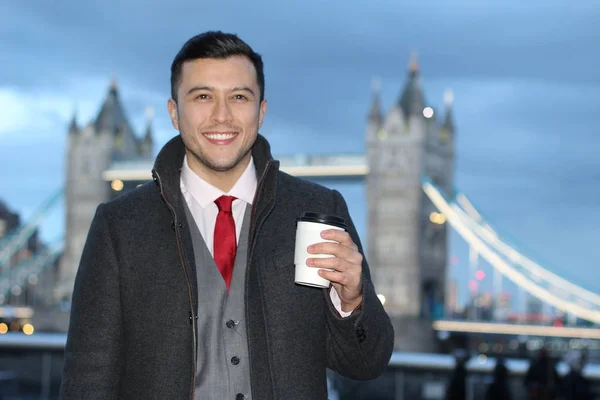 英国ロンドンのタワーブリッジの前でコーヒーを紙コップでハンサムな若いビジネスマンのクローズアップ肖像画 — ストック写真