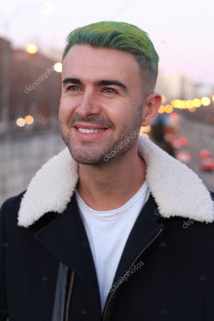 Trendsetter with green hair smiling, blurred city background 
