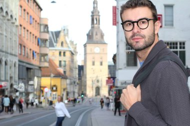 Eski Avrupa şehrinin sokaklarında günlük giysiler içinde yakışıklı bir gencin yakın plan portresi.