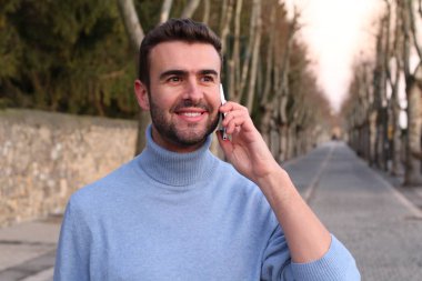 close-up portrait of handsome young man talking by phone on street