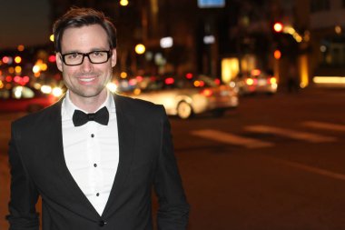 smokinli ve papyonlu yakışıklı bir delikanlının akşam vakti şehir caddesinde yakın plan fotoğrafı.