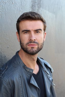 Duvarın önündeki yakışıklı sakallı adamın yakın plan portresi.