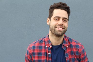 Gri duvarın önündeki yakışıklı genç adamın yakın plan portresi.