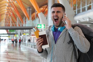 Genç bir adam havaalanından telefon alıyor.