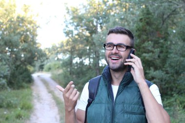 Doğada telefonla konuşan yakışıklı genç adamın yakın plan portresi.