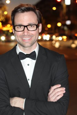 smokinli ve papyonlu yakışıklı bir delikanlının akşam vakti şehir caddesinde yakın plan fotoğrafı.