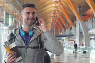 Genç bir adam havaalanından telefon alıyor.