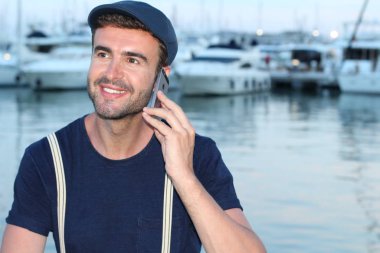 Limanda telefonla konuşan yakışıklı bir gencin yakın plan portresi.