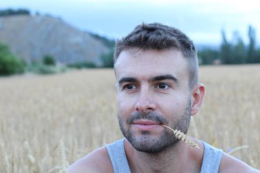 Akşamları buğday tarlasında yakışıklı bir gencin yakın plan portresi.